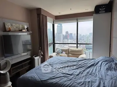 Cozy bedroom with city view, featuring modern decor and large windows for natural light.