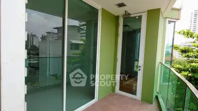 Spacious balcony with glass railing and green walls in modern apartment.