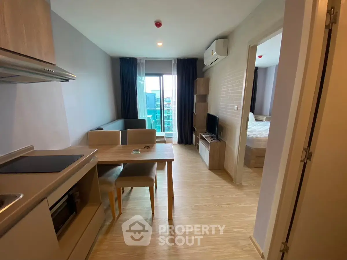 Modern apartment interior with open kitchen and cozy living area, featuring natural light and stylish furnishings.