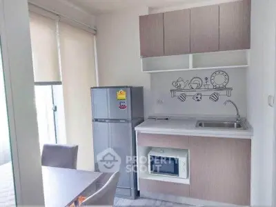 Modern kitchen with sleek cabinetry, fridge, and microwave in a compact open layout.