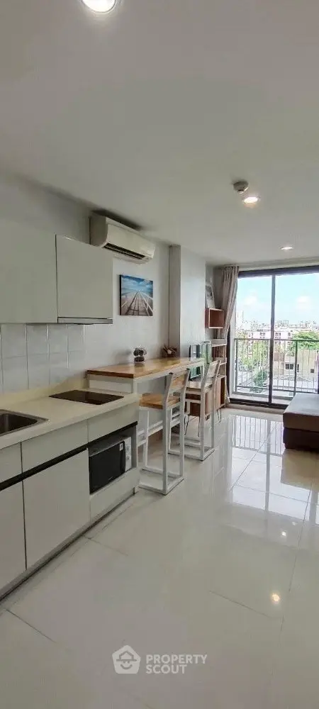 Modern kitchen with sleek white cabinets and breakfast bar overlooking a scenic balcony view.