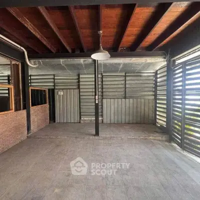 Spacious industrial-style interior with exposed beams and tiled flooring, perfect for creative use.