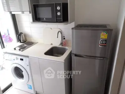 Compact modern kitchen with appliances including fridge, microwave, and washing machine.