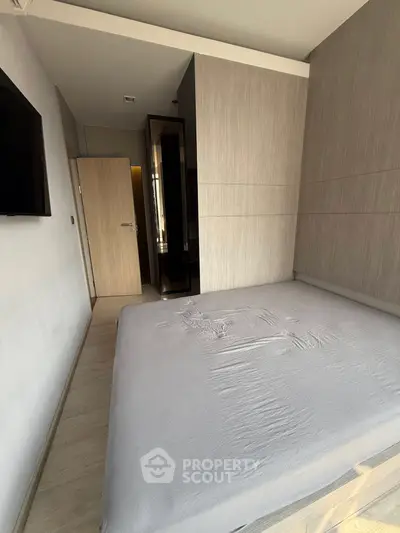 Modern bedroom with sleek design and neutral tones, featuring a wall-mounted TV and minimalist decor.