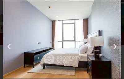 Modern bedroom with stylish furniture and large window offering natural light.