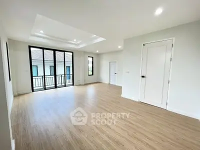 Spacious empty room with wooden flooring and large windows in modern home.