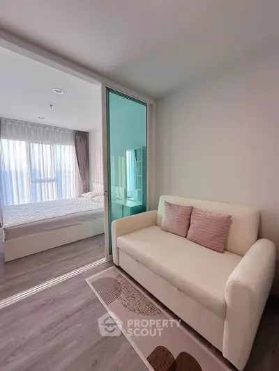 Modern apartment with cozy living area and bright bedroom separated by glass partition.