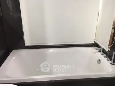 Luxurious bathroom featuring a sleek modern bathtub with elegant fixtures, perfect for relaxation.