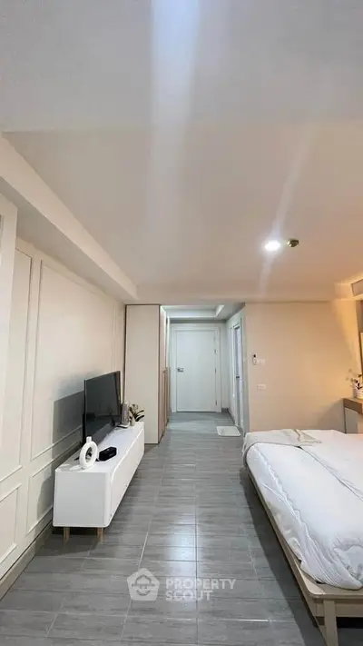 Modern bedroom with sleek design and flat-screen TV, featuring neutral tones and stylish decor.