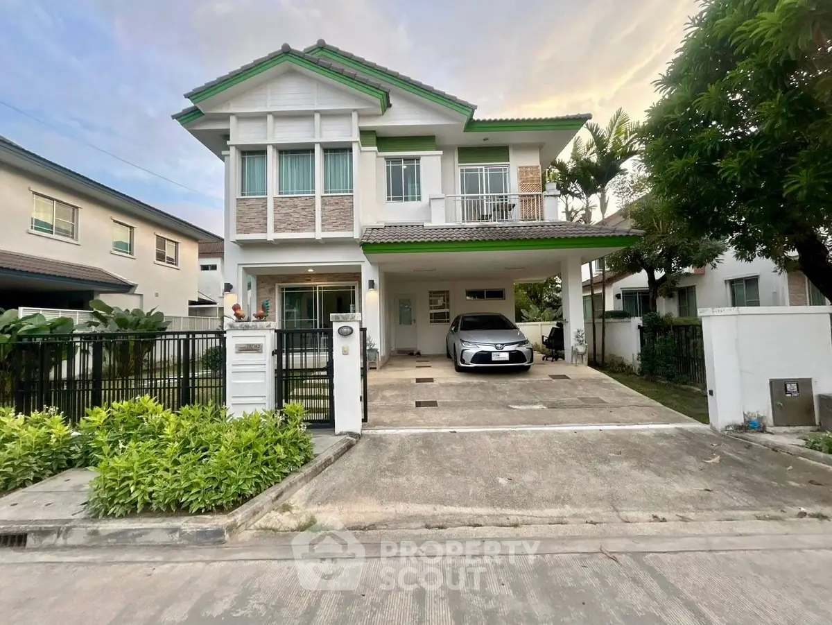 Charming two-story house with driveway and lush greenery in a serene neighborhood.
