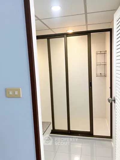 Modern bathroom with sliding glass shower doors and sleek tile flooring.