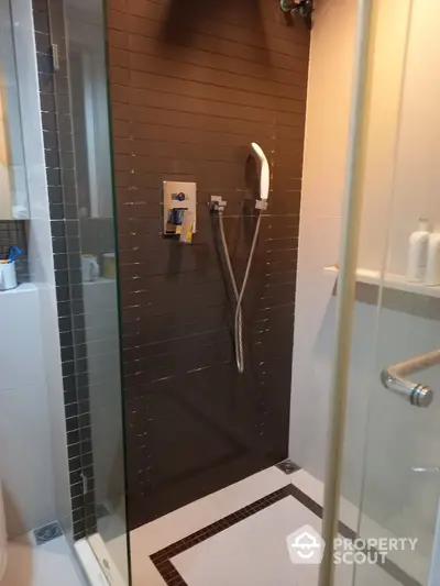 Modern bathroom with sleek glass shower enclosure and dark tile walls, offering a minimalist and sophisticated design for urban living.