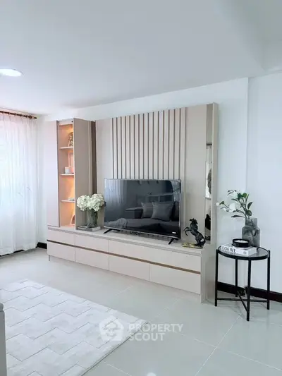 Modern living room with sleek TV unit and elegant decor, featuring soft lighting and a cozy atmosphere.