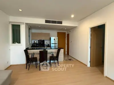 Modern open-layout kitchen and dining area with sleek appliances and wooden flooring.