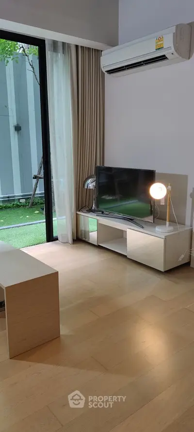 Modern living room with large window, air conditioning, and sleek TV setup.
