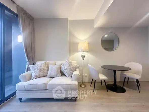 Modern living room with elegant sofa and dining area, featuring stylish decor and ample natural light.