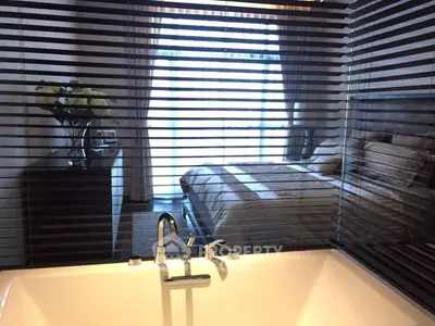 Luxurious bedroom with bathtub and elegant decor, featuring a large window with natural light.
