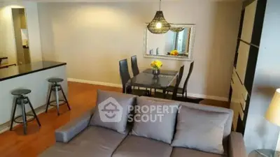 Spacious living room with modern decor and dining area, featuring stylish lighting and comfortable seating.