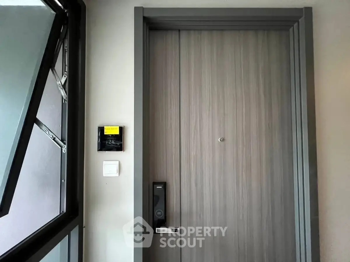 Modern apartment entrance with sleek wooden door and digital lock system.