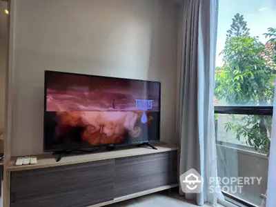 Modern living room with large TV and natural light from window