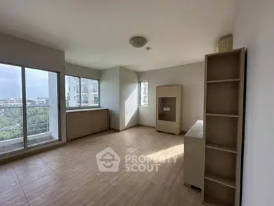 Spacious unfurnished room with large windows and wooden flooring, offering ample natural light and city views.