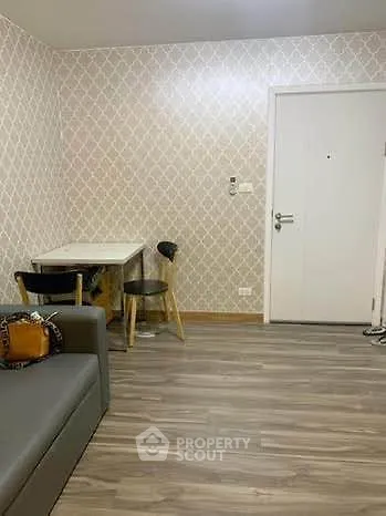 Modern living room with stylish wallpaper and wooden flooring, featuring a cozy seating area and a small dining table.