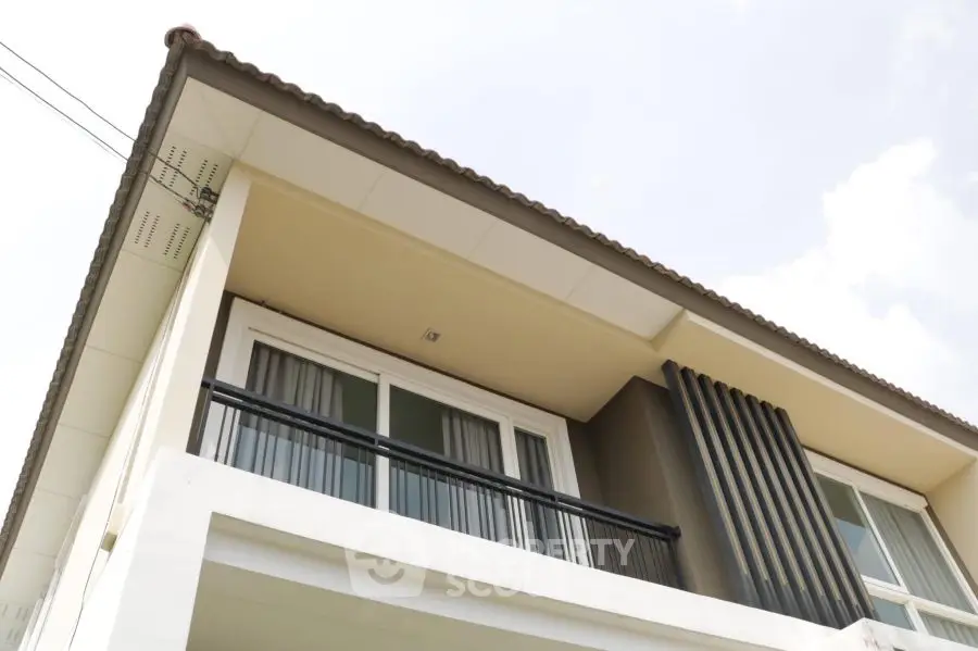 Modern two-story house exterior with sleek balcony and contemporary design.