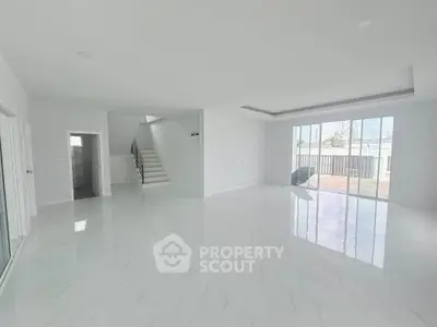 Spacious modern living room with sleek white flooring and large windows for natural light.