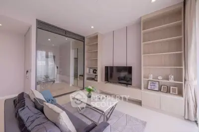 Modern living room with sleek design, large TV, and elegant shelving in a bright apartment.