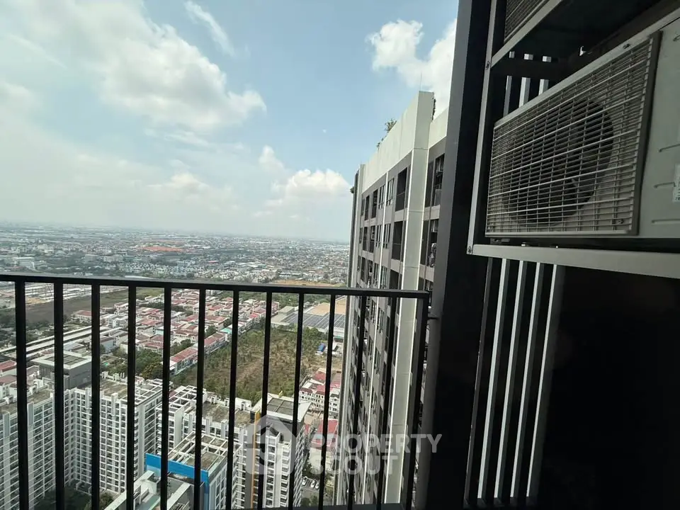 Stunning high-rise balcony view overlooking cityscape with clear skies and modern architecture.