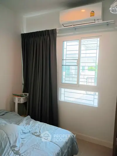 Cozy bedroom with natural light and air conditioning, perfect for comfortable living.
