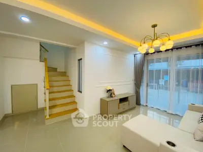 Modern living room with elegant lighting and staircase, featuring a cozy seating area and stylish decor.