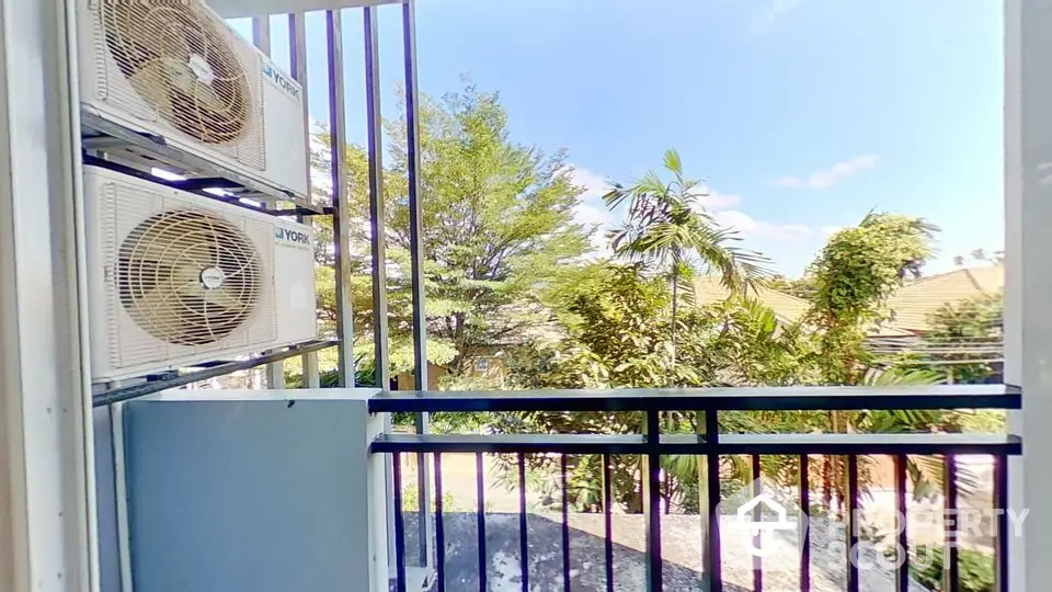 Charming balcony with lush green view and air conditioning units.