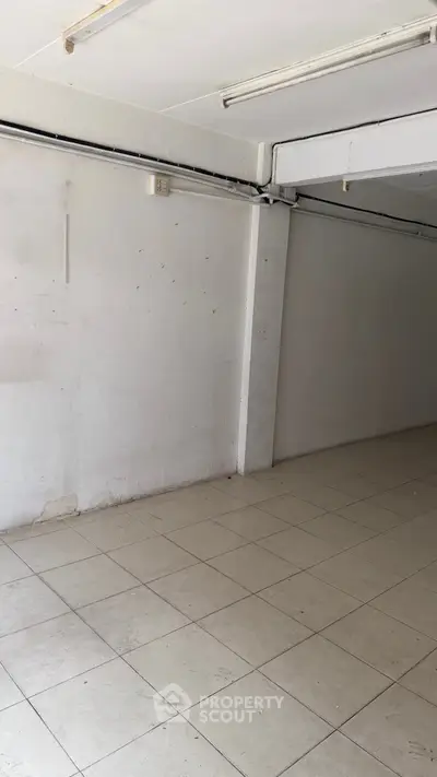 Spacious empty room with tiled flooring and white walls, ideal for customization.