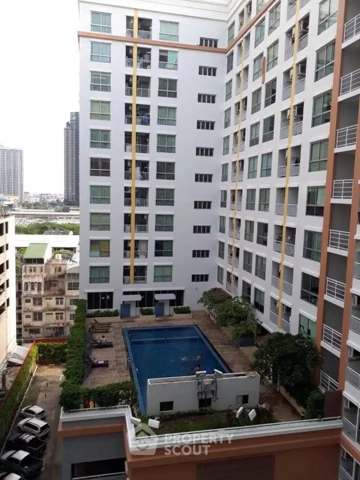 Modern condominium with pool view in urban setting, showcasing high-rise architecture and cityscape.
