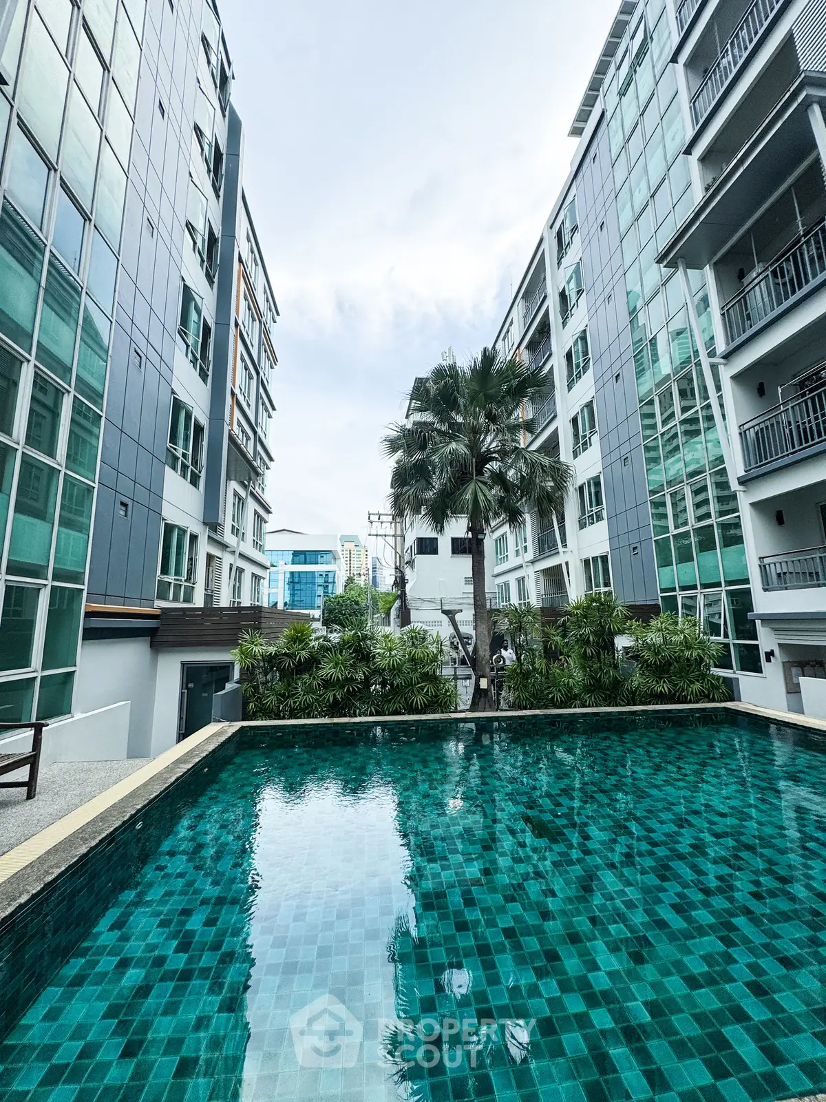 Luxurious apartment complex with a stunning pool and modern architecture, perfect for urban living.