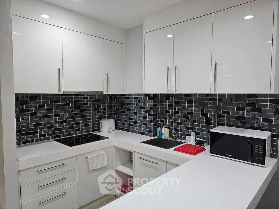 Modern kitchen with sleek white cabinets and stylish black tile backsplash.