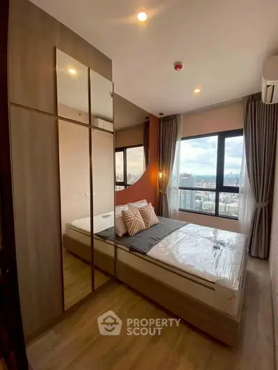 Modern bedroom with city view, featuring large windows and stylish decor.