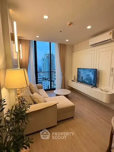 Modern living room with city view, featuring cozy seating and elegant decor in a high-rise apartment.