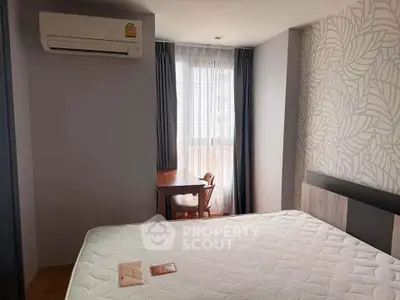 Cozy bedroom with air conditioning and natural light, featuring a stylish accent wall and a comfortable bed.