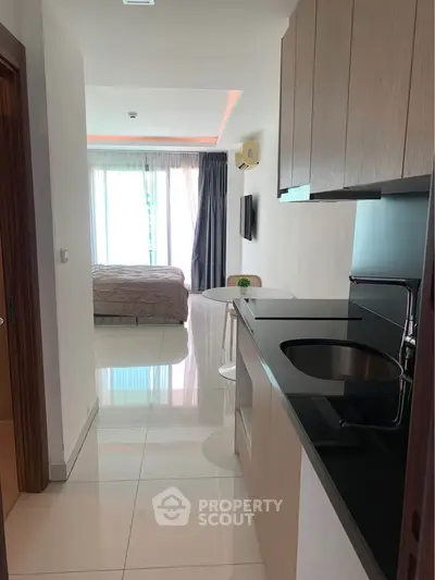 Modern studio apartment with sleek kitchen and cozy bedroom area, featuring large windows for natural light.