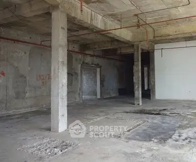 Spacious industrial-style open space with concrete pillars and exposed ceiling.