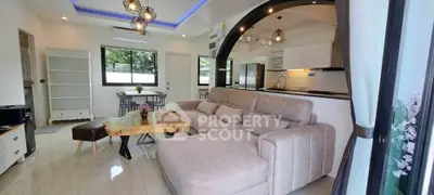 Modern open-plan living room with stylish furniture and kitchen area, featuring unique wooden coffee table.