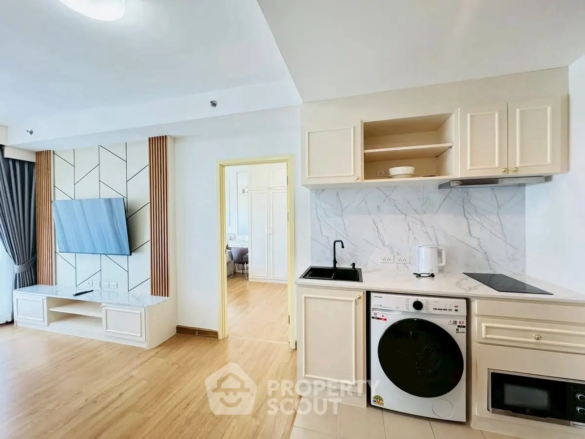 Modern open-layout kitchen with integrated washing machine and stylish living area.
