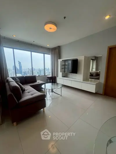 Modern living room with city view, featuring sleek furniture and large windows.
