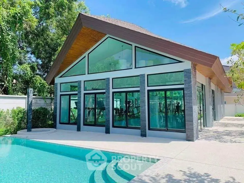 Stunning modern house with large glass windows and a sparkling pool, perfect for luxury living.
