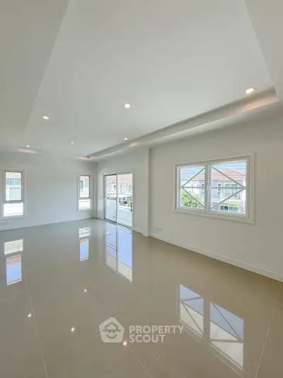 Spacious modern living room with large windows and glossy tiled floors, offering abundant natural light and a serene view.