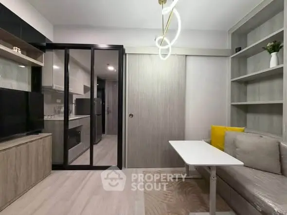 Modern compact living room with sliding glass doors to kitchen, stylish lighting, and cozy seating area.