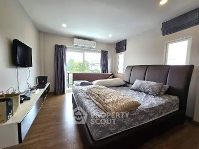 Spacious bedroom with modern decor and large windows offering natural light.