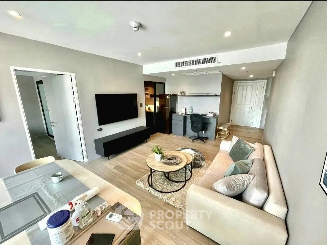 Modern living room with stylish decor and open layout, featuring a cozy sofa and wall-mounted TV.